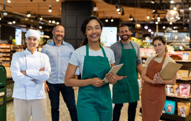 Happy team of Latin American employees working at a supermarket and looking at the camera smiling