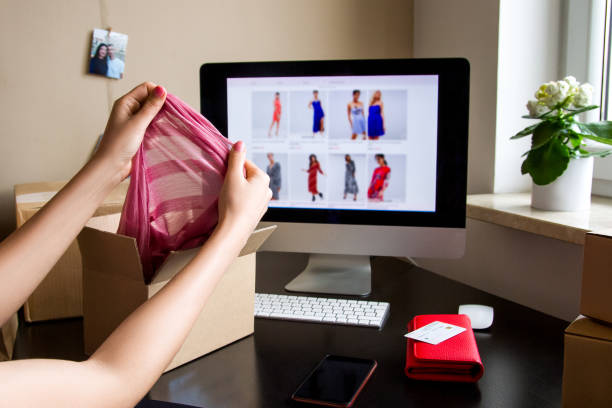 Hands take clothes out of the box. Computer screen, credit card, wallet.